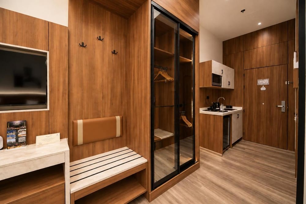 Double Room – Disability Access: glass-door wardrobe, luggage bench and TV on wood panelling